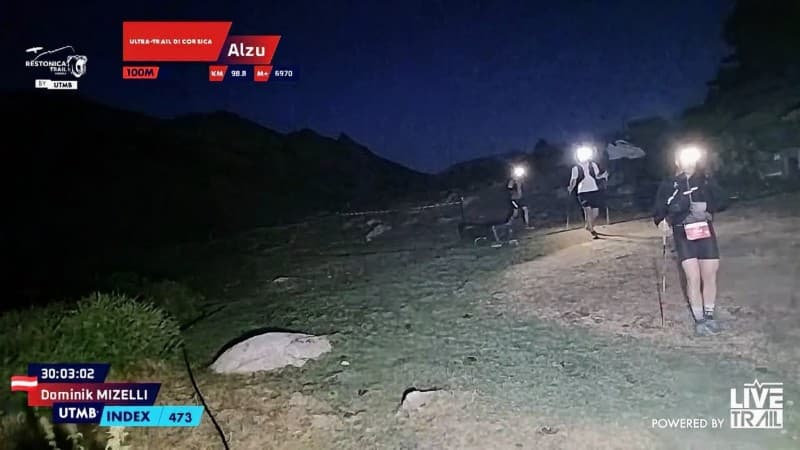 Trail runners hiking at night with headlamps illuminating their path on a rugged outdoor trail.
